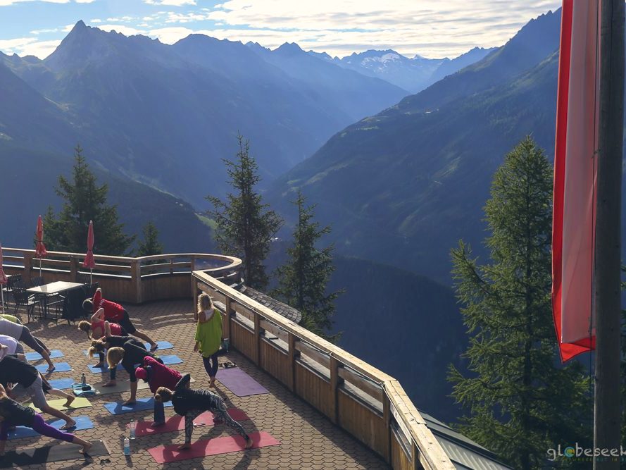 An acro yoga balance on the terrace against the mountains.