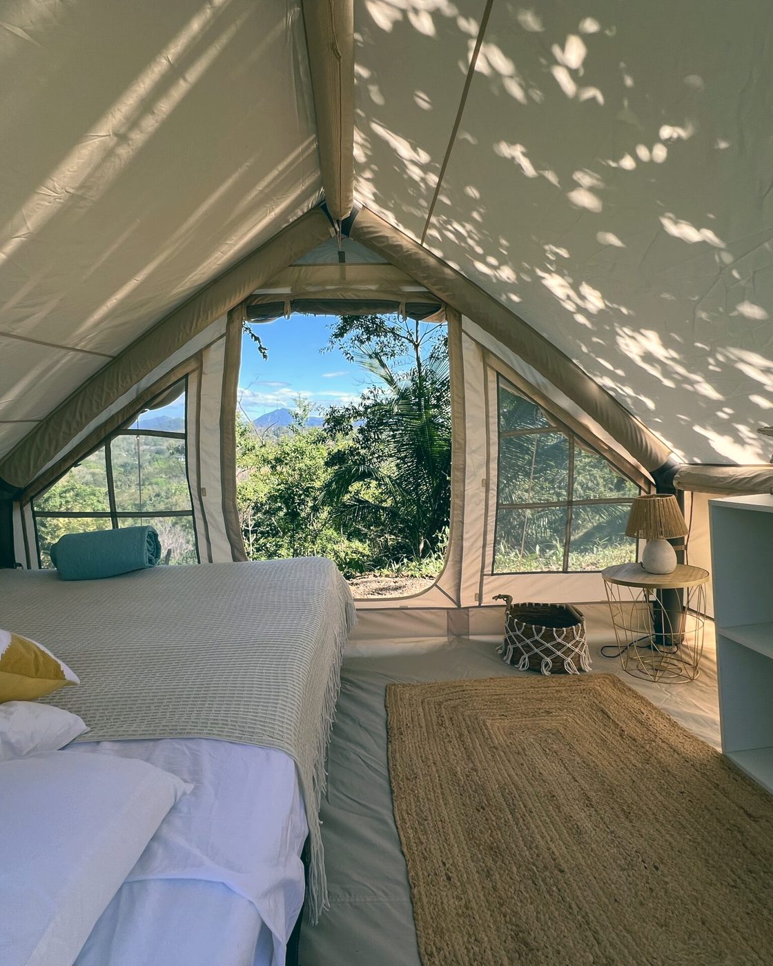 A glamping tent under the canopy, bed open to the jungle and ocean breeze.