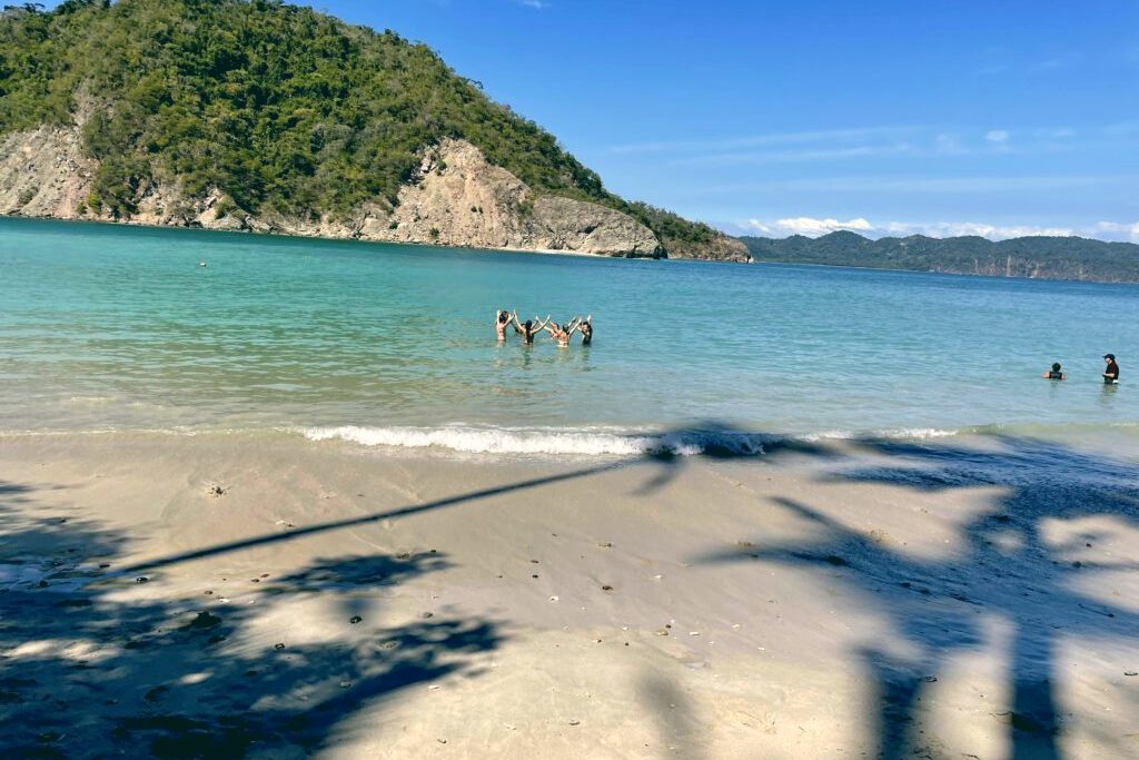 A quiet turquoise beach on the Nicoya Peninsula, an island on the horizon.