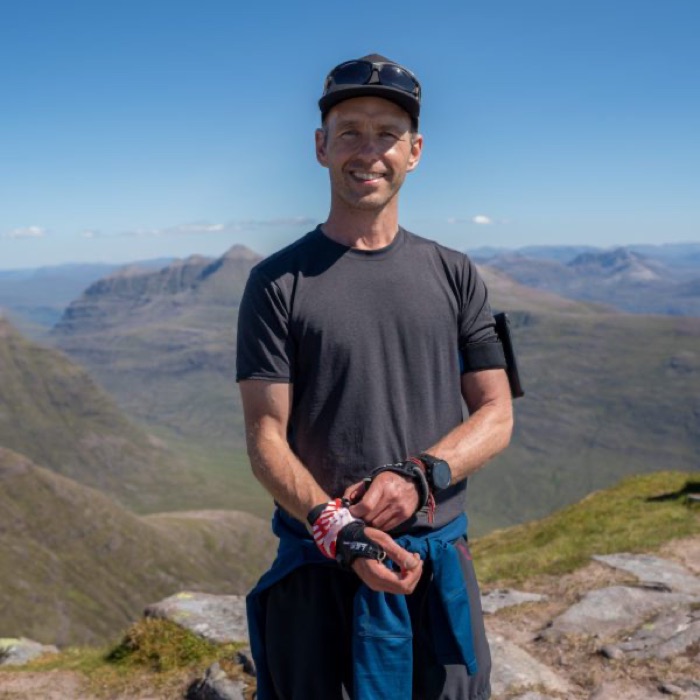 Douglas, smiling on a sunlit mountain ridge.