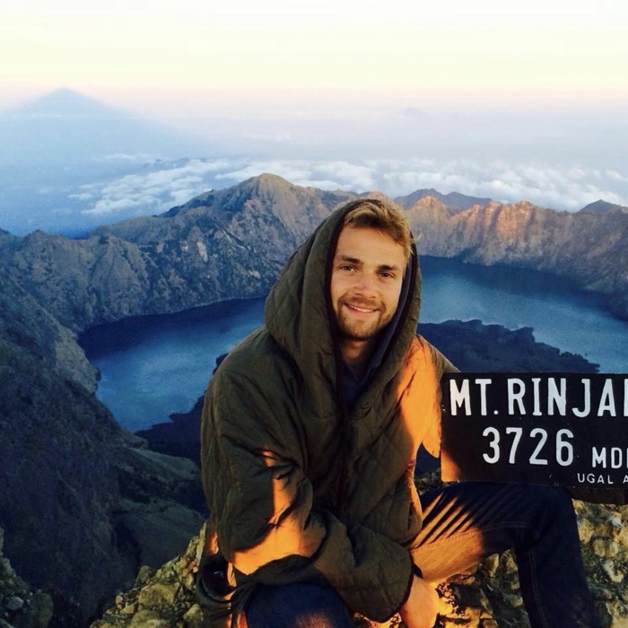 Elias on a mountain summit at sunrise, above the clouds.